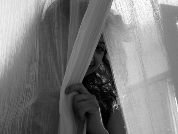 A girl behind a curtain.