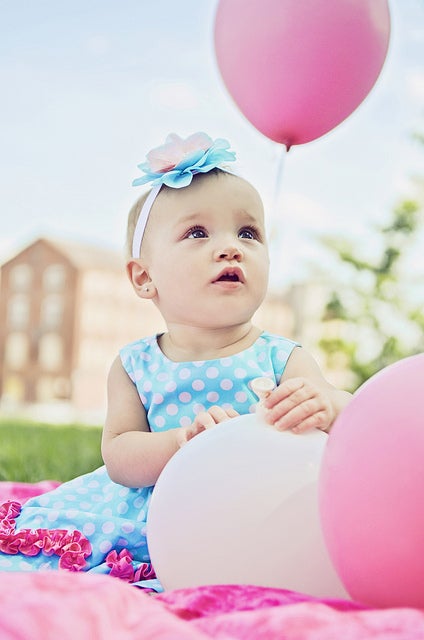 A baby with a pink balloon.