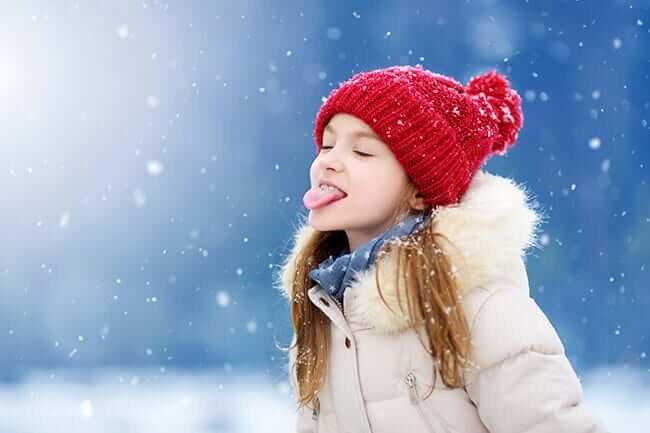 girl sticking tongue out to catch snow
