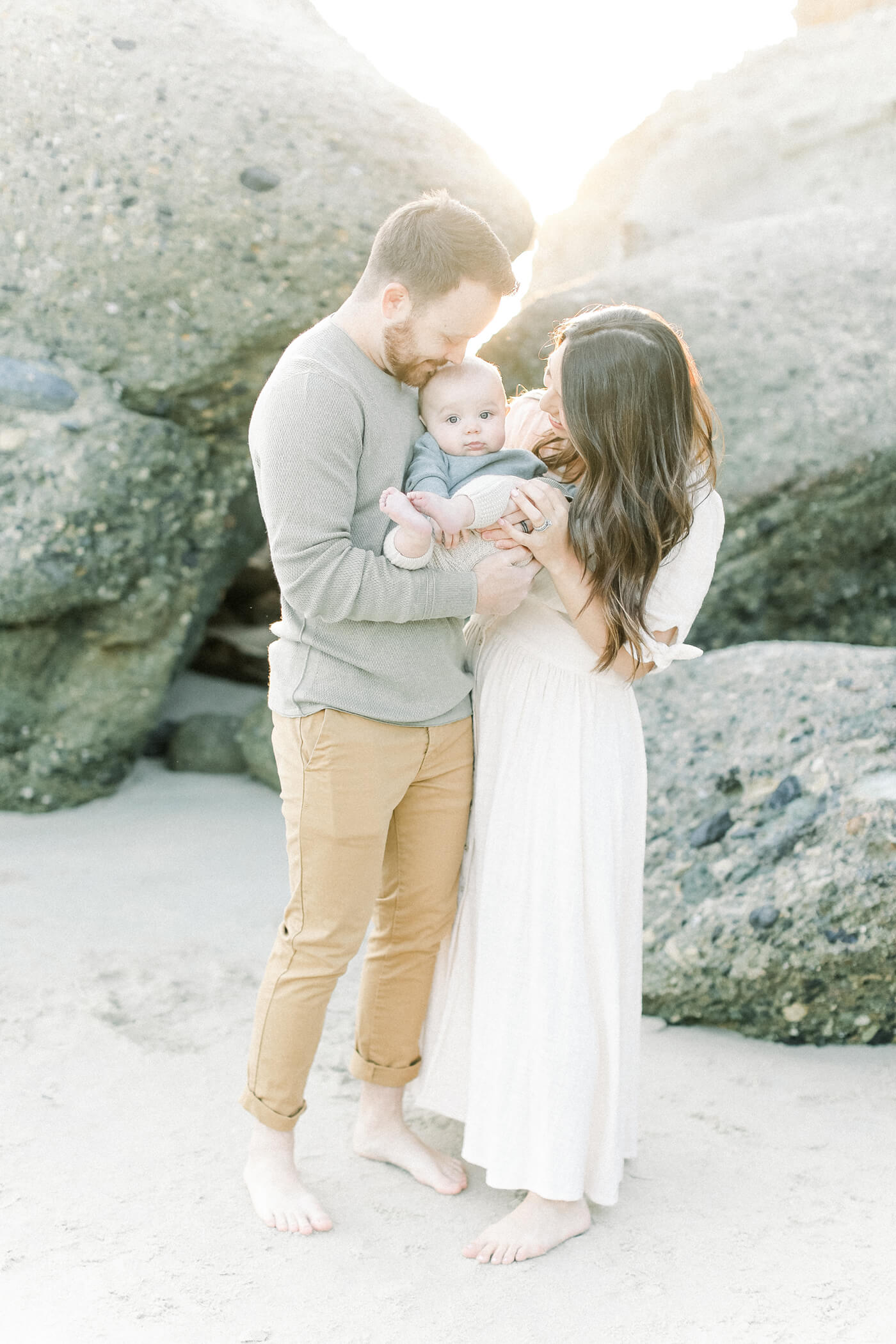 family kissing baby for beach portraits