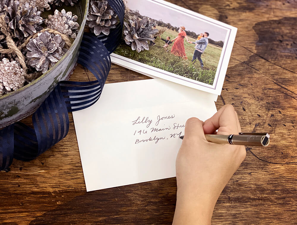 woman addressing a holiday card manufactured by Printique