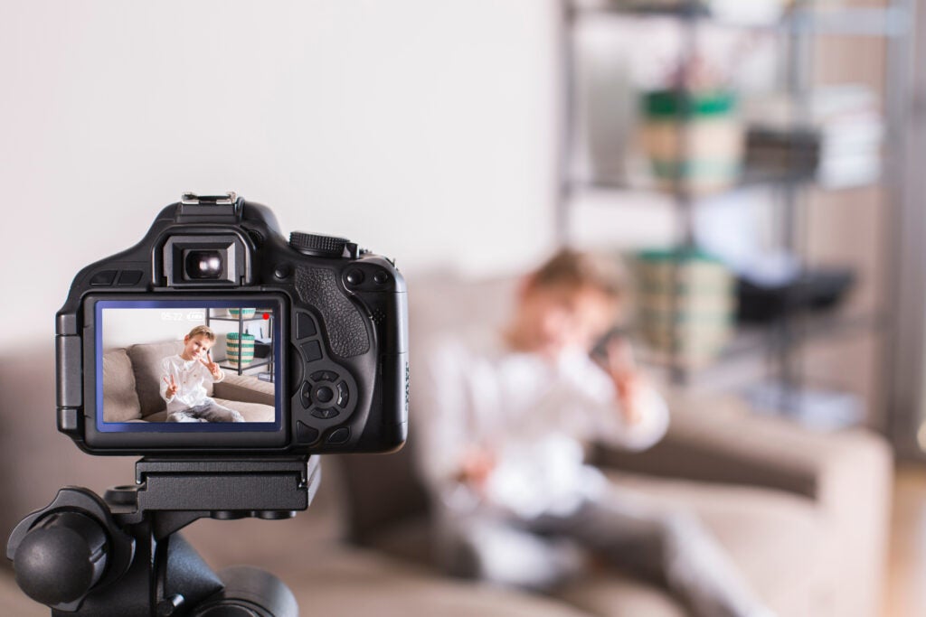 Kid practices holiday card photoshoot with camera on tripod.