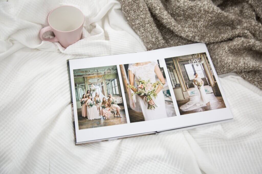 Bride holds flowers and poses with bridesmaids in wedding photo album.