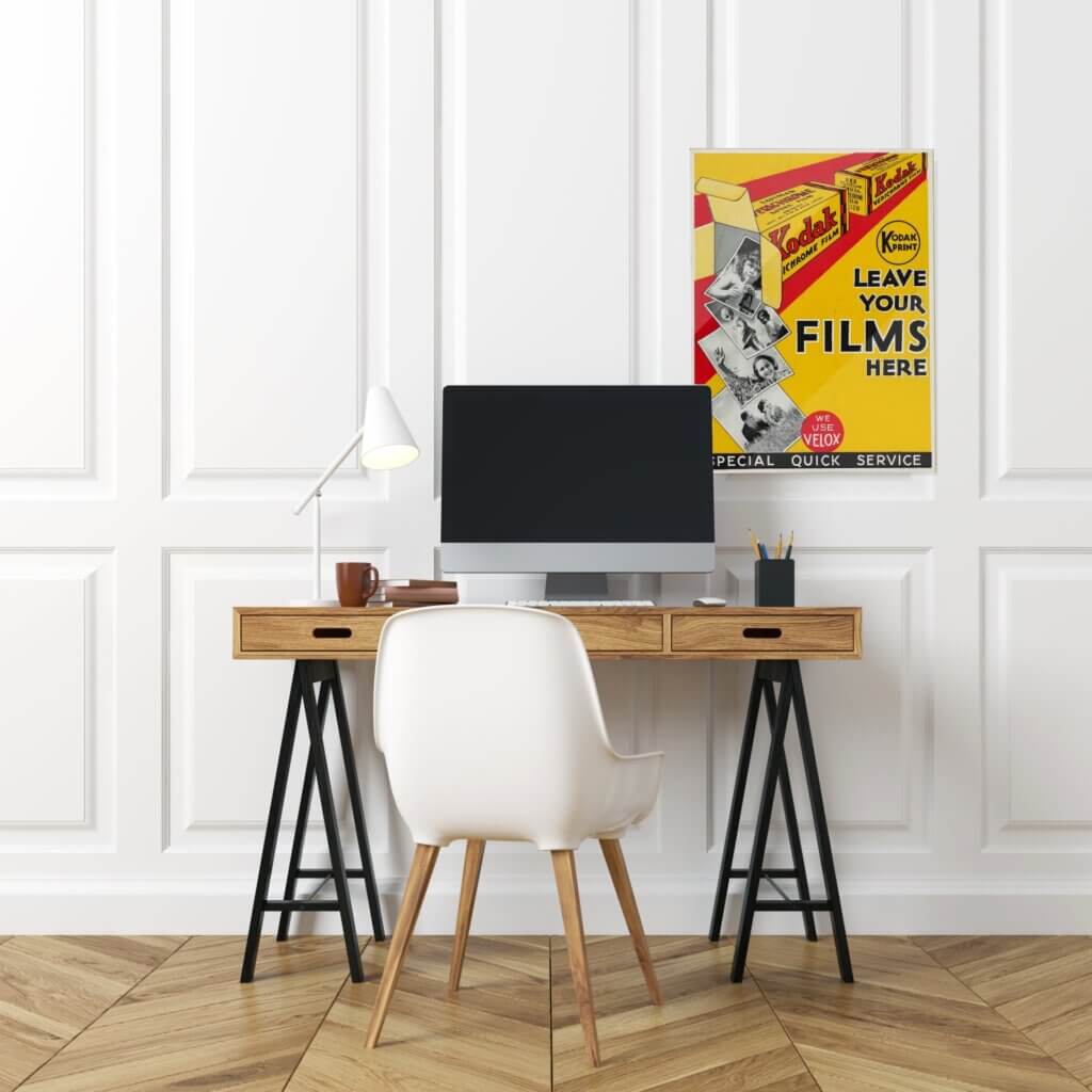 A vintage kodak free printable hangs on the wall in an office space, adding bold colors to an otherwise bland room.