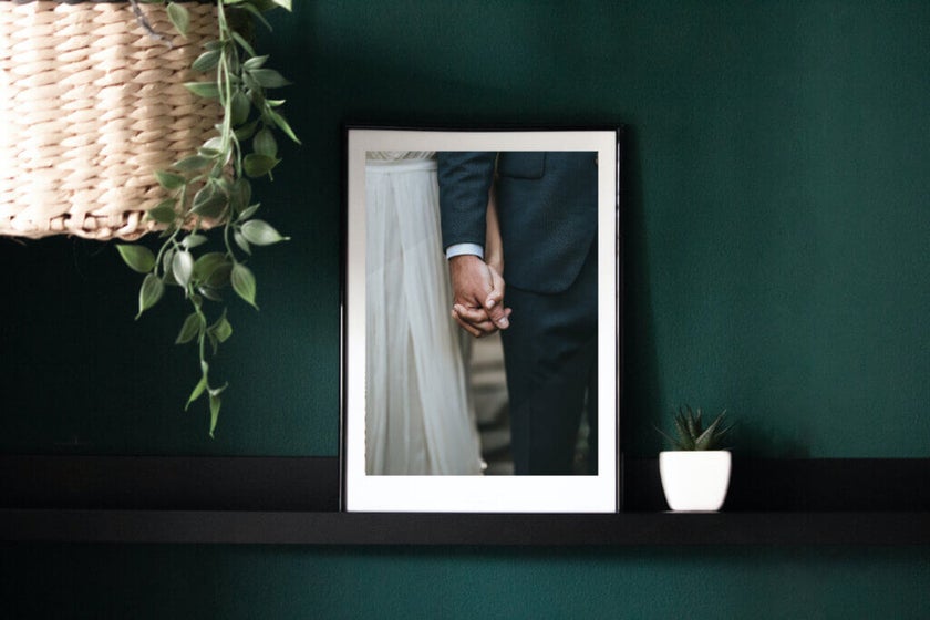 Couple holds hand on wedding day in a framed photo print.