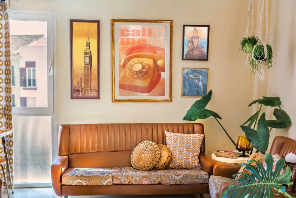 Retro posters decorate the wall behind a vintage-inspired couch, demonstrating a retro home aesthetic.