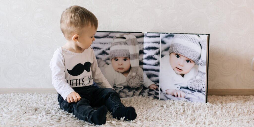 A little boy sits beside his baby photo book.