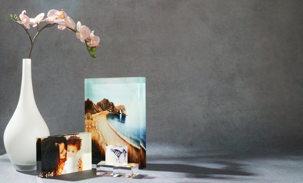 A custom acrylic print glows in nature sunlight, alongside a blossoming orchid.