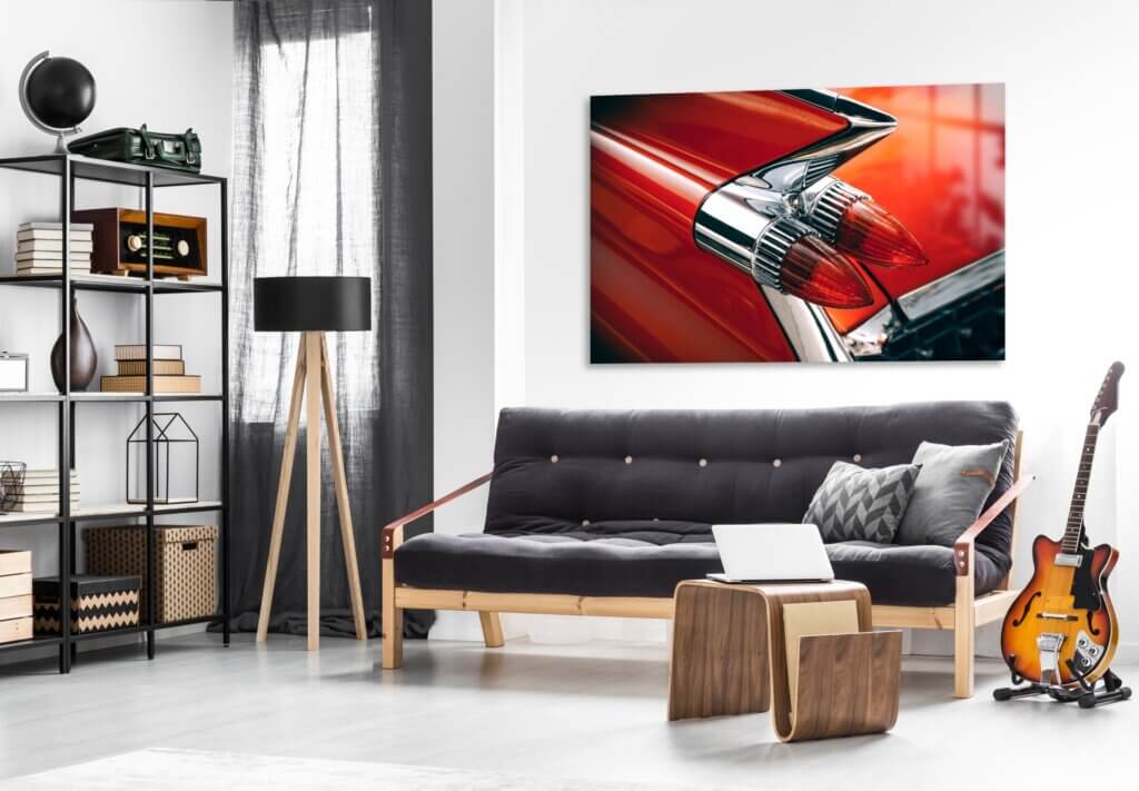 A vibrant and large metal print decorates the space behind a couch with a photo of a red car.
