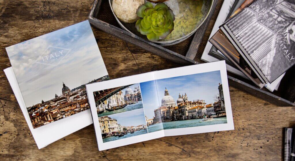 A travel album of a vacation to Italy sits open on a coffee table.